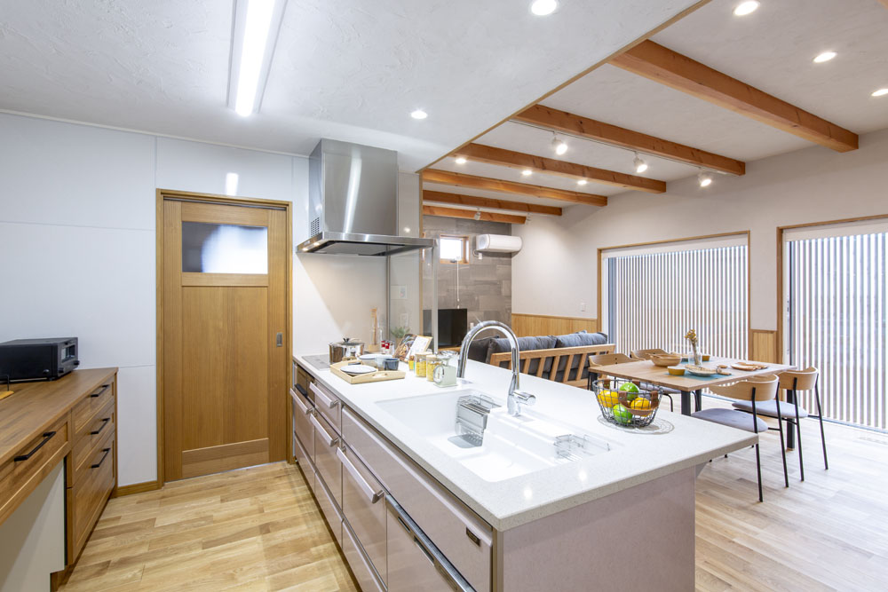 Open-concept kitchen with an island sink, stainless appliances, and a dining area with a wooden table nearby.